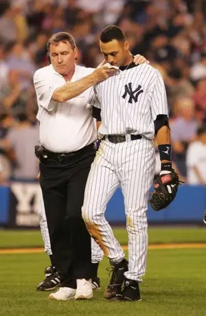 Trainer Gene Monahan helps Derek Jeter of the