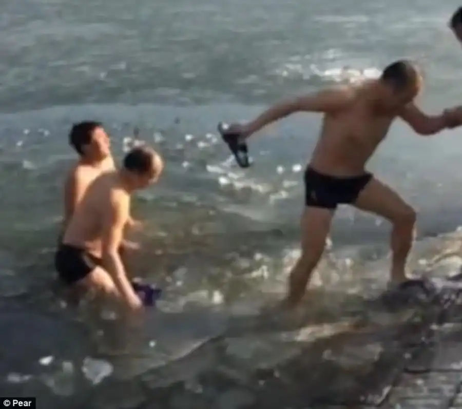 The trio manages to get out of the water with the help of other onlookers next to the river