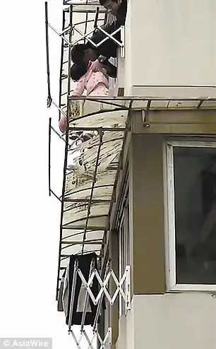 Another onlooker holds onto Mr Long's legs during the dangerous rescue