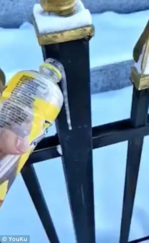 He tests with a bottle of red tea as he pours it onto a metal gate