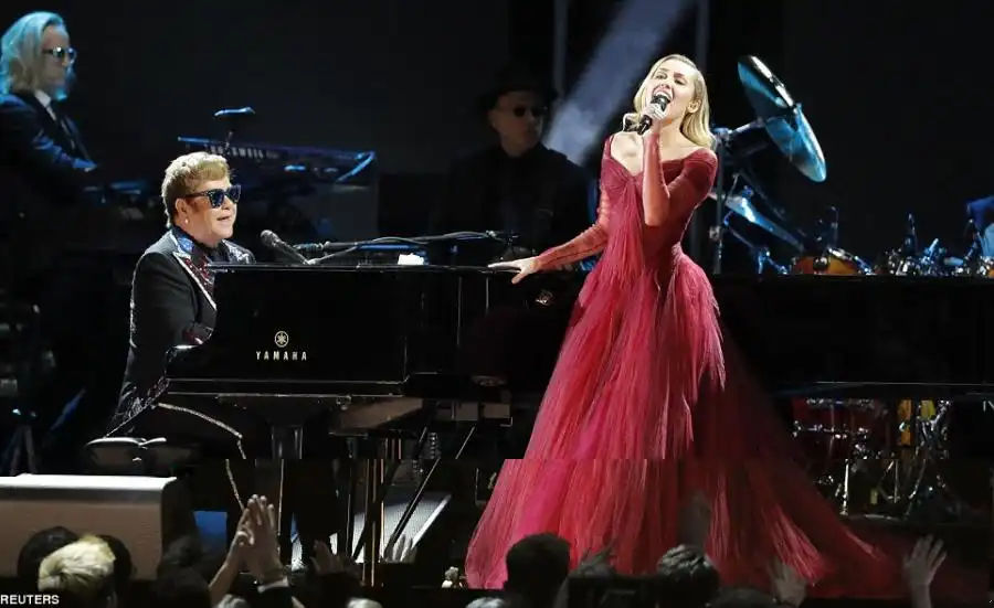 Fun times: The unlikely duo performed Tiny Dancer as the 70-year-old legendary musician was being honored with the Recording Academy President's Merit Award with longtime writing partner Bernie Taupin who played piano