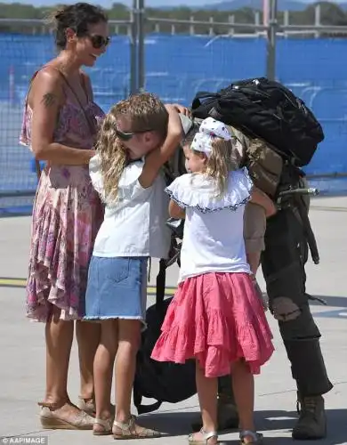 A pair of young girls grasped their father in firm embraces as their emotional mother watched on