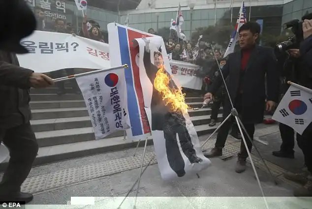 Demonstrators used a blowtorch to burn Kim's photo, a North Korean flag and a 'unification flag' that athletes of the rival Koreas will carry together during the opening ceremony