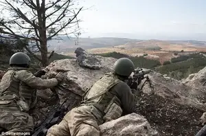 Turkish soldiers look out over the Syrian territory after airstrikes in the northwestern Kurdish region of Afrin