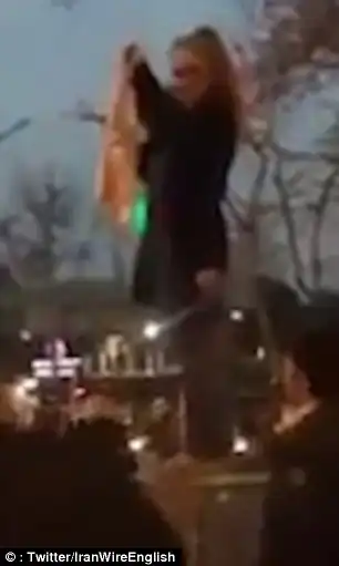 In the latest clip, the woman is seen raising the headscarf above her head by a set of traffic lights in Tehran
