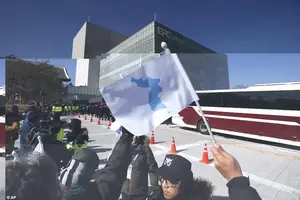 Around 20 well-wishers waved blue and white unification flags to welcome them as they drove into South Korea