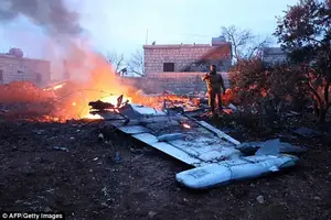 Crashed: A Rebel fighter is seen taking a picture of the downed Sukhoi-25 fighter jet in the the Syrian city of Saraqib, southwest of Aleppo