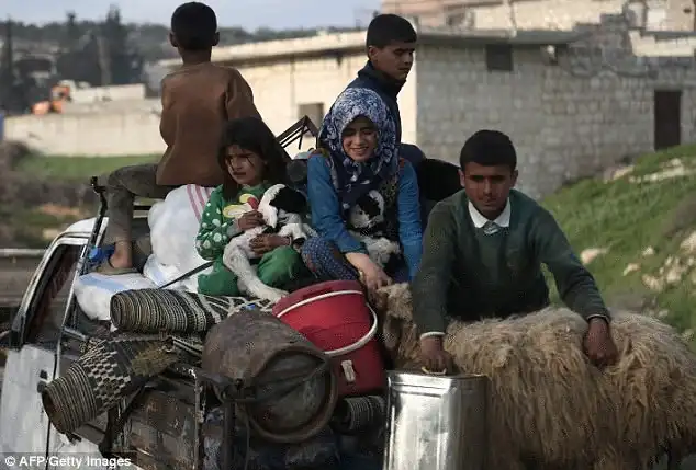 Syrian civilians fleeing Afrin after Turkey stated its army and allied rebels surrounded the Kurdish city in northern Syria, pass through the village of Anab northwest of the city