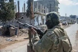 Invasion: A member of Free Syrian Army, backed by Turkish Armed Forces is seen as he stands guard at Rajos town center near Afrin town in Afrin
