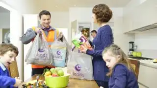 A food deliveryman puts bags of groceries on a table