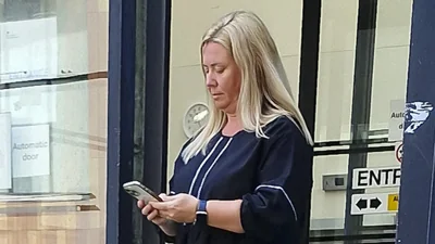 Photograph of Lyndsey Amos outside court looking down at a mobile phone.