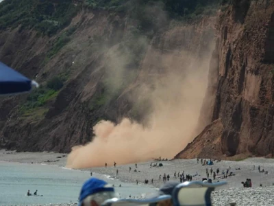 Story from Jam Press (Huge Rock Fall) Pictured: A huge plume of red dust billowing across the sea after the massive rockfall. VIDEO: Thousands of tons of rock crash down onto beach right next to sunbathers Thousands of tons of rock crashed onto a beach, narrowly avoiding sunbathers. A huge plume of red dust billowed across the sea after the massive rockfall. The crash cut off a few beachgoers who were there at the time, and a lifeboat was launched to rescue them. The heart-stopping moment was captured on camera at Budleigh Salterton, Devon, on Saturday.