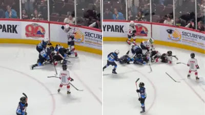Young ice hockey players in a chaotic brawl on the ice during an intermission game.