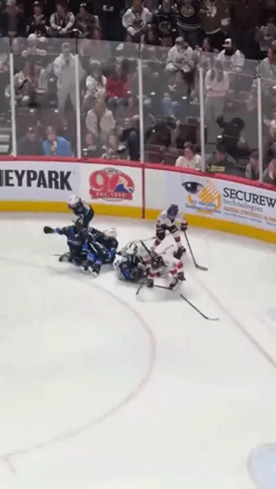 A young ice hockey goalie charging into a fight, flattening another player on the ice.