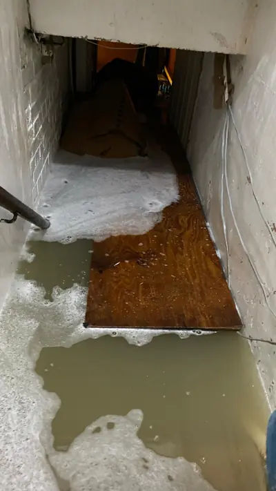 The flooded basement of Ten Ten chicken shop on Caledonian Road, submerged in murky water.